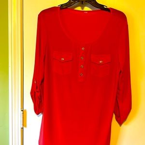 Coral polyester and spandex buttoned top with buttoned sleeves.
